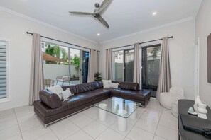 Relax in this inviting living space with a comfortable sofa, coffee table, and side table, surrounded by large windows offering a view of the outdoors.