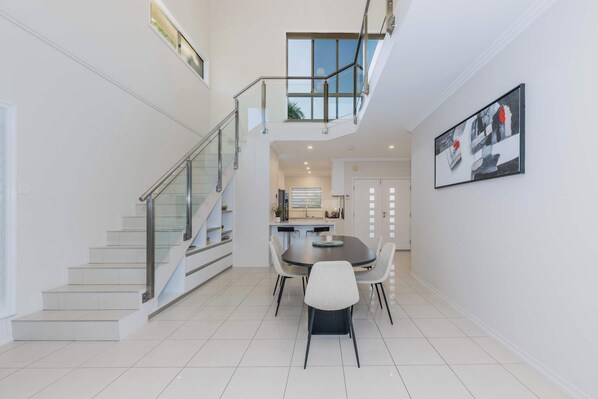 Staircase leads to an upper level, with a dining area featuring a round table and chairs.