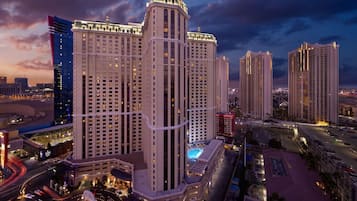 Een hoog hotel met meerdere verdiepingen, een centrale binnentuin met zwembad, en omliggende wolkenkrabbers.