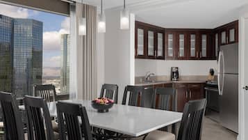 Een moderne keuken met donkere houten kasten, een roestvrijstalen koelkast en een eethoek met een witte tafel en stoelen.