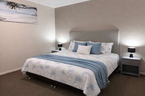 Un dormitorio con una cama, dos mesitas de noche y una lámpara de pared.