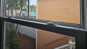A window view of a building with a green roof, a pool, and palm trees. - Top Gulf Coast Perdido Key Getaway Island Vacation (Perdido Key)
