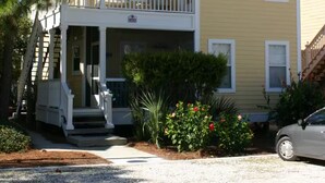 A two-story yellow building with a balcony, a covered porch, and a gravel driveway. - Top Gulf Coast Perdido Key Getaway Island Vacation (Perdido Key)