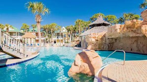 A pool area with a clear blue pool, palm trees, and a rock formation. - Top Gulf Coast Perdido Key Getaway Island Vacation (Perdido Key)