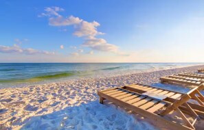 Ein Strand mit Holzliegen und freiem Blick auf das Meer.