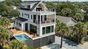 A modern two-story house with a balcony, a swimming pool, and a view of the surrounding greenery. - The Lookout | Private Pool | Steps to Beach & Pier | Newly Built (Folly Beach)
