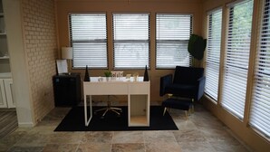 A room with a desk, chair, and windows.