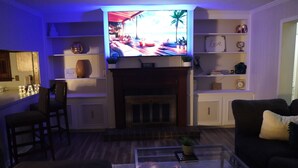 A living room with a television, a fireplace, a coffee table, and seating.