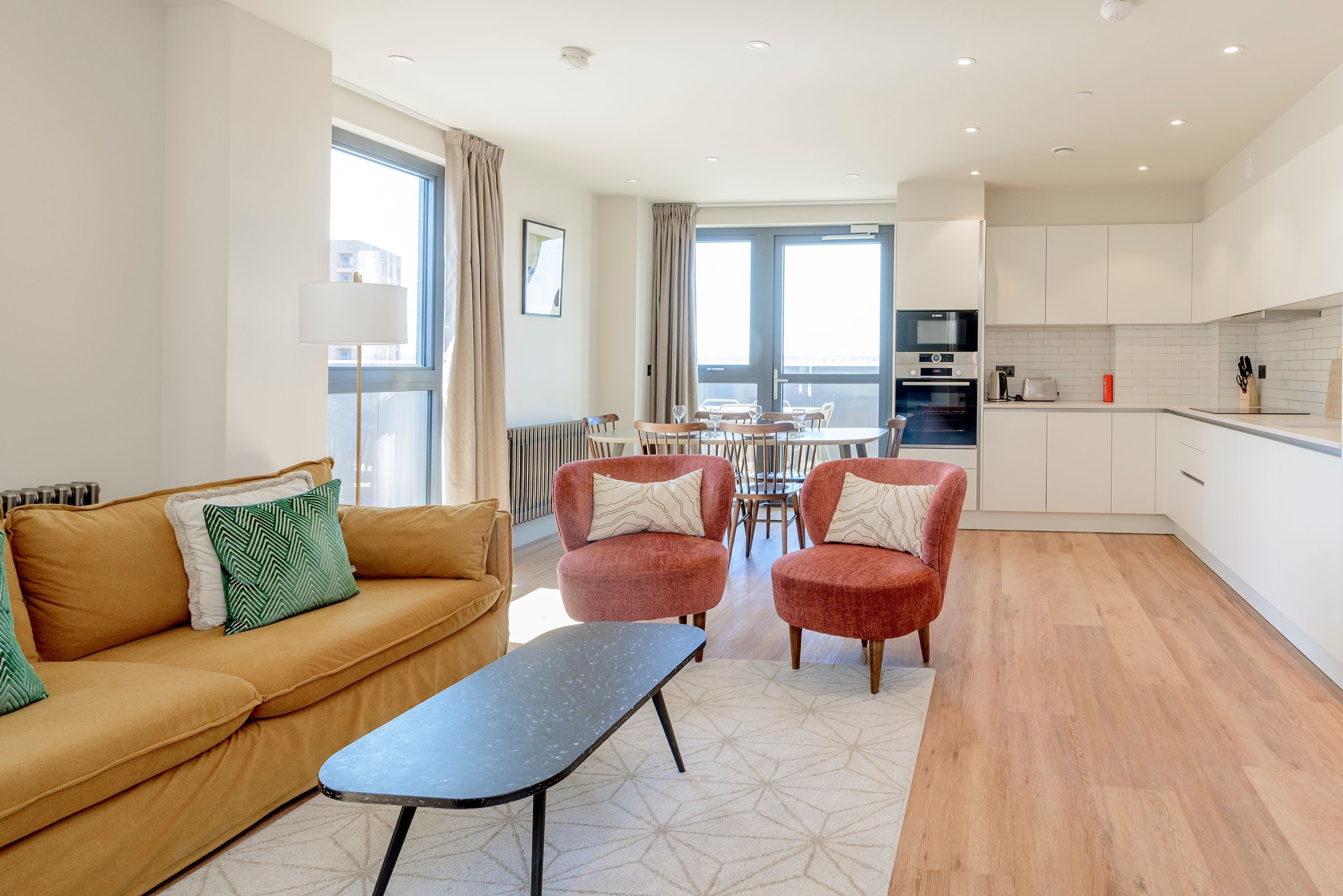 Un salon moderne comprenant un canapé, des fauteuils, une table basse et un coin repas avec une table et des chaises.