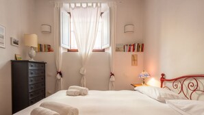 A hotel room with a bed, a dresser, a nightstand, a lamp, and a window with curtains. - One-bedroom apartment with Patio n.2 (Firenze)