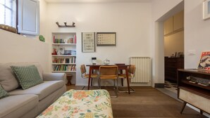 A cozy room with a bed, a sofa, a desk with a chair, a bookshelf, and a radiator. - One-bedroom apartment with Patio n.2 (Firenze)