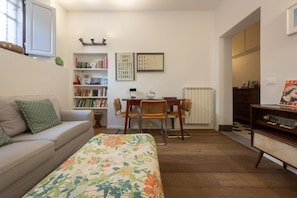 Une pièce confortable avec un lit, un canapé, un bureau avec une chaise, une bibliothèque et un radiateur.