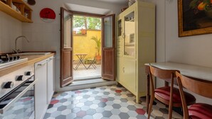 A compact kitchen with a dining area, a yellow wall, and a view through an open door. - One-bedroom apartment with Patio n.2 (Firenze)