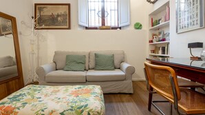 A room with a sofa, a chair, a bed, a desk, and a window with curtains. - One-bedroom apartment with Patio n.2 (Firenze)