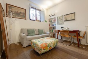 A living room with a sofa, ottoman, and a dining area with chairs and a table.