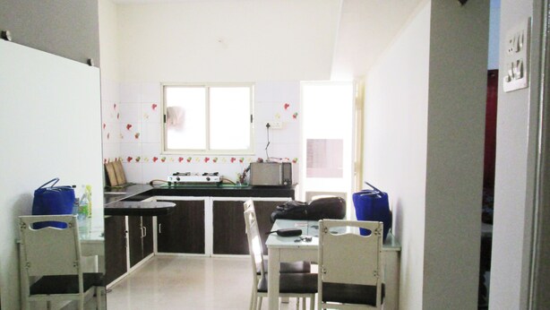 A compact kitchen with a dining area, white walls, and a ceiling fan.
