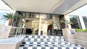 Entrada de um edifício moderno, com piso xadrez, teto curvo e fachada de vidro.