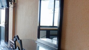 Uma mesa de madeira escura com um espelho grande e uma cadeira em um quarto com paredes bege e piso em azulejo.