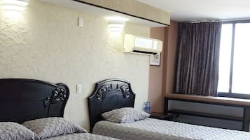 Habitación de hotel con dos camas, un ventanal con cortinas y un equipo de aire acondicionado instalado en la pared.