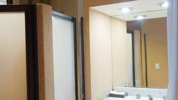 A bathroom with a large mirror, a sink with two faucets, and a towel hanging on a rack.