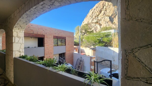 A courtyard with a stone archway, a brick building, and a mountain in the background. - Hotel El Descanso (Bernal)