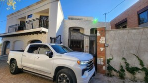 A white pickup truck parked in front of a building with a stone facade, a balcony, and a gated entrance. - Hotel El Descanso (Bernal)