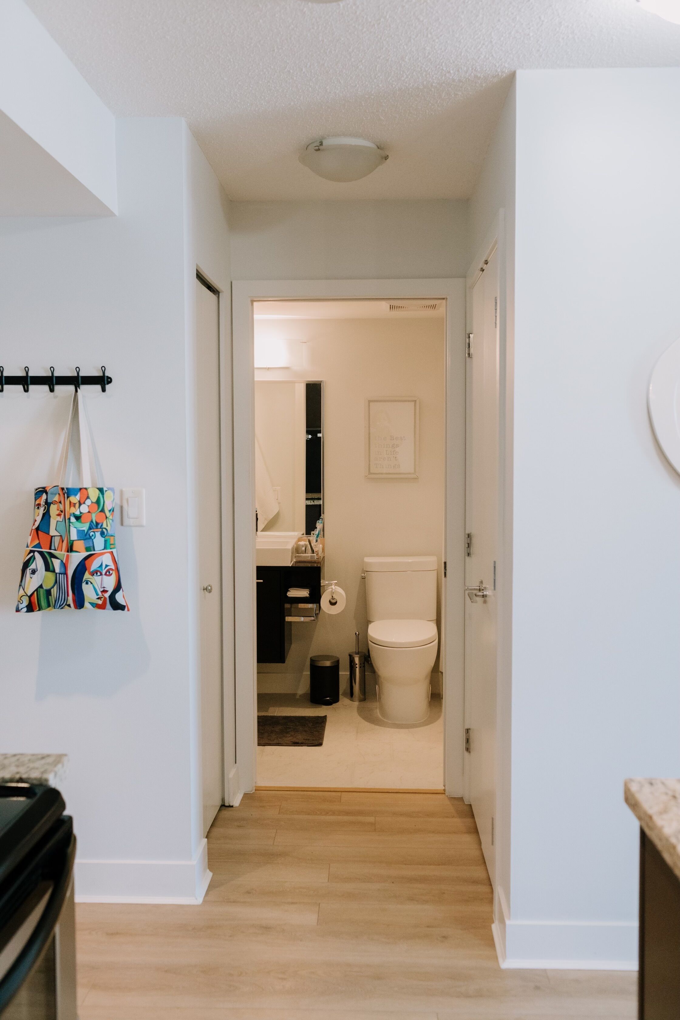 Un pasillo que conduce a un baño con inodoro, lavamanos y espejo.