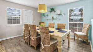 A dining area with a wooden table, wicker chairs, and a yellow pendant light.