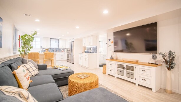 Un salon moderne avec un canapé gris, un téléviseur à écran plat et un meuble en bois.