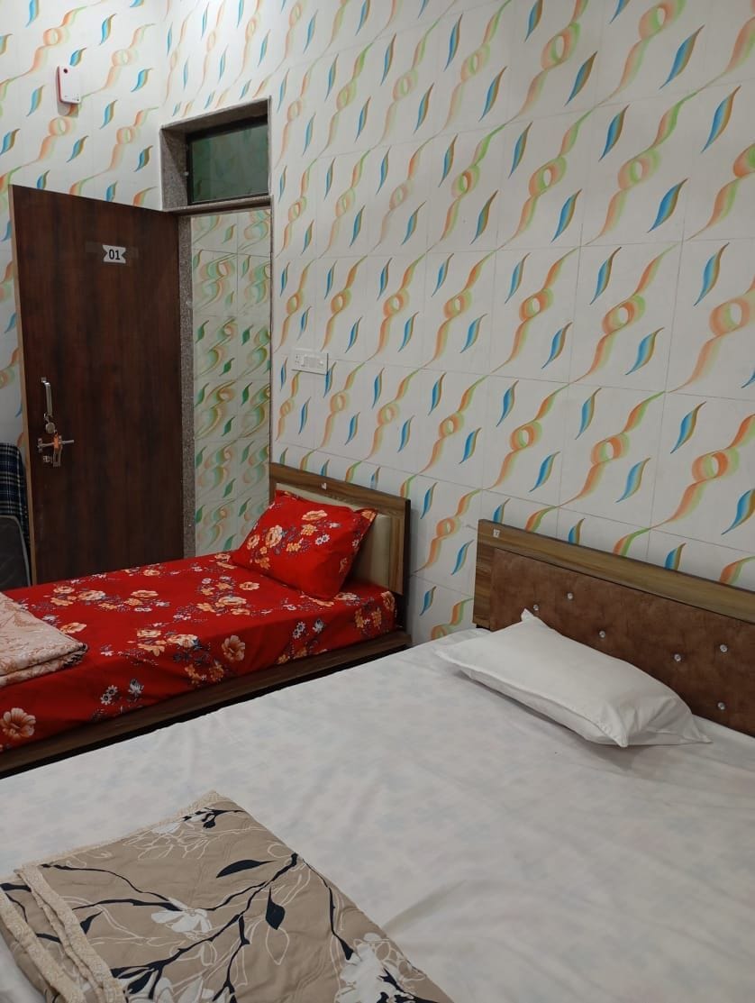 A room with a bed, a wooden wardrobe, and a patterned wall.