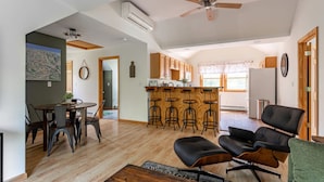 A spacious living area with a dining table, chairs, a sofa, and a bar area with stools. - Couple s Oasis Pool Stream Firepit Steam Room (Saugerties)