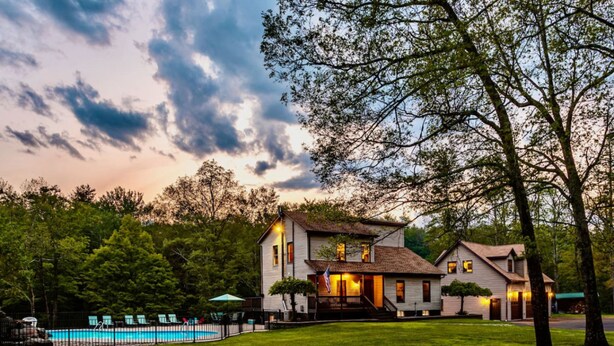 A two-story house with a swimming pool, surrounded by trees and a well-maintained lawn. - Couple s Oasis Pool Stream Firepit Steam Room (Saugerties)