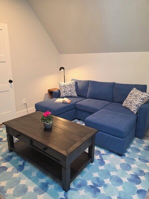Een woonkamer met een hoekbank, een salontafel en gekleurde kussens.