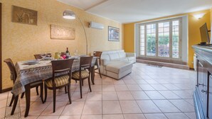A dining area with a table set for four, a sofa, and a television on a cabinet.