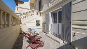 A narrow courtyard with a wooden cart, a Samsung air conditioning unit, and a staircase leading to a balcony.