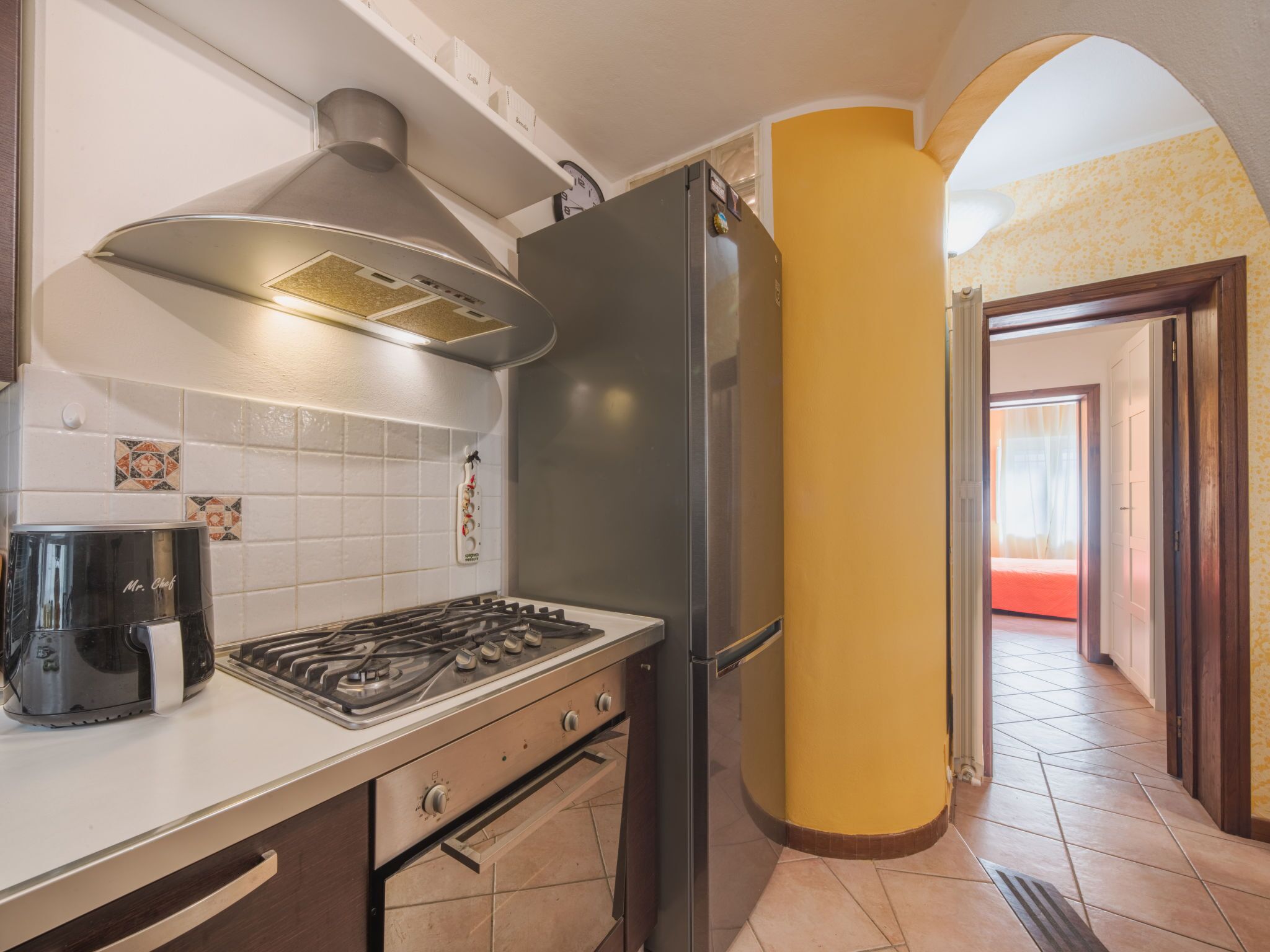 A kitchen with a gas stove, a stainless steel refrigerator, and a coffee maker.