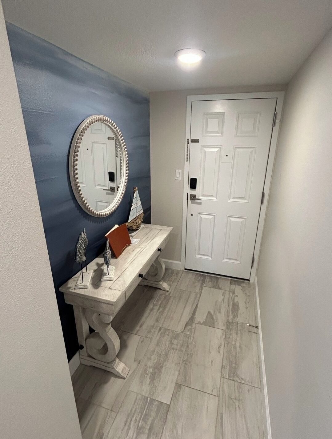 Un baño con tocador blanco, espejo redondo y una puerta.