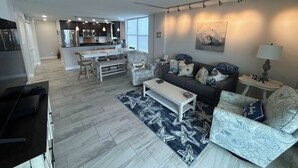 A modern living room with a sofa, coffee table, and a dining area with chairs.