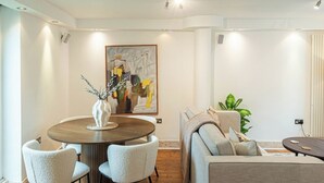 A modern dining area with a round table, white chairs, and a vase with branches.