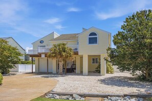 A two-story house with a covered front porch, a small attached garage, and a gravel driveway.