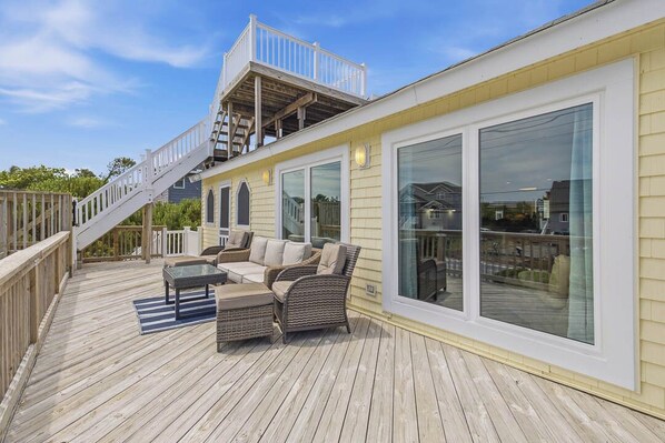 A deck with outdoor furniture, a staircase, and large windows.