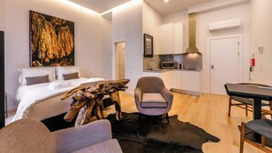 Un appartement moderne doté d’un grand lit, d’un coin repas, d’une cuisine et d’un salon avec une table basse en bois au design unique.