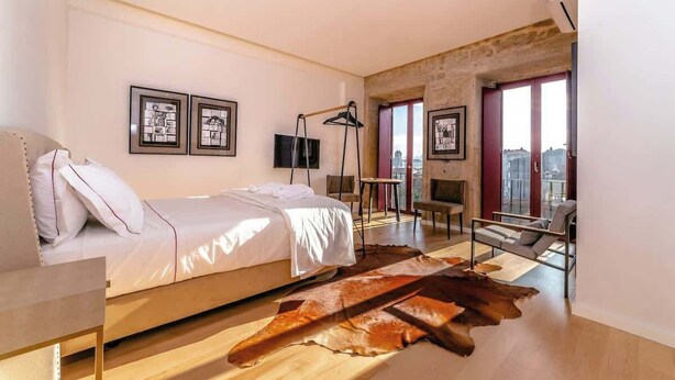 Quarto moderno com cama, tapete de couro, escrivaninha e uma cadeira.