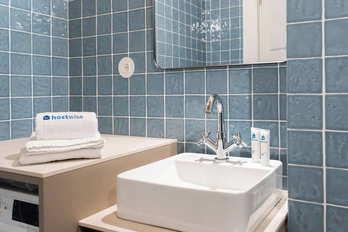 A bathroom with a white sink, a mirror, and a towel with 'hostwise' branding.