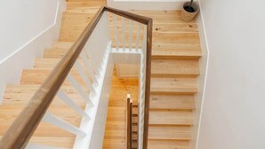 A wooden staircase with white railings and a metal handrail.