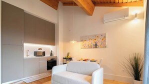 A modern kitchen with grey cabinets, a white sofa, and a painting of flowers on the wall.