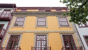 A building with three windows and a central door, each with decorative iron railings.