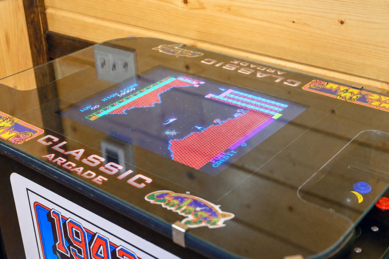 Une borne d’arcade classique, dotée d’un écran affichant un jeu, d’un lecteur de pièces et d’une étiquette indiquant « BORNE D’ARCADE CLASSIQUE ».