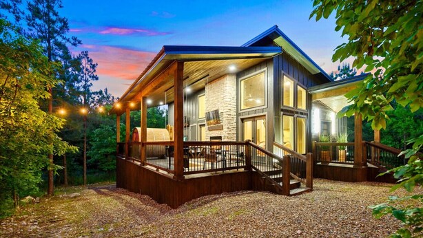A modern house with a covered porch, stone walls, and a gravel driveway.