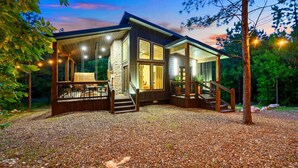 A modern house with a stone facade, large windows, and a wooden deck.